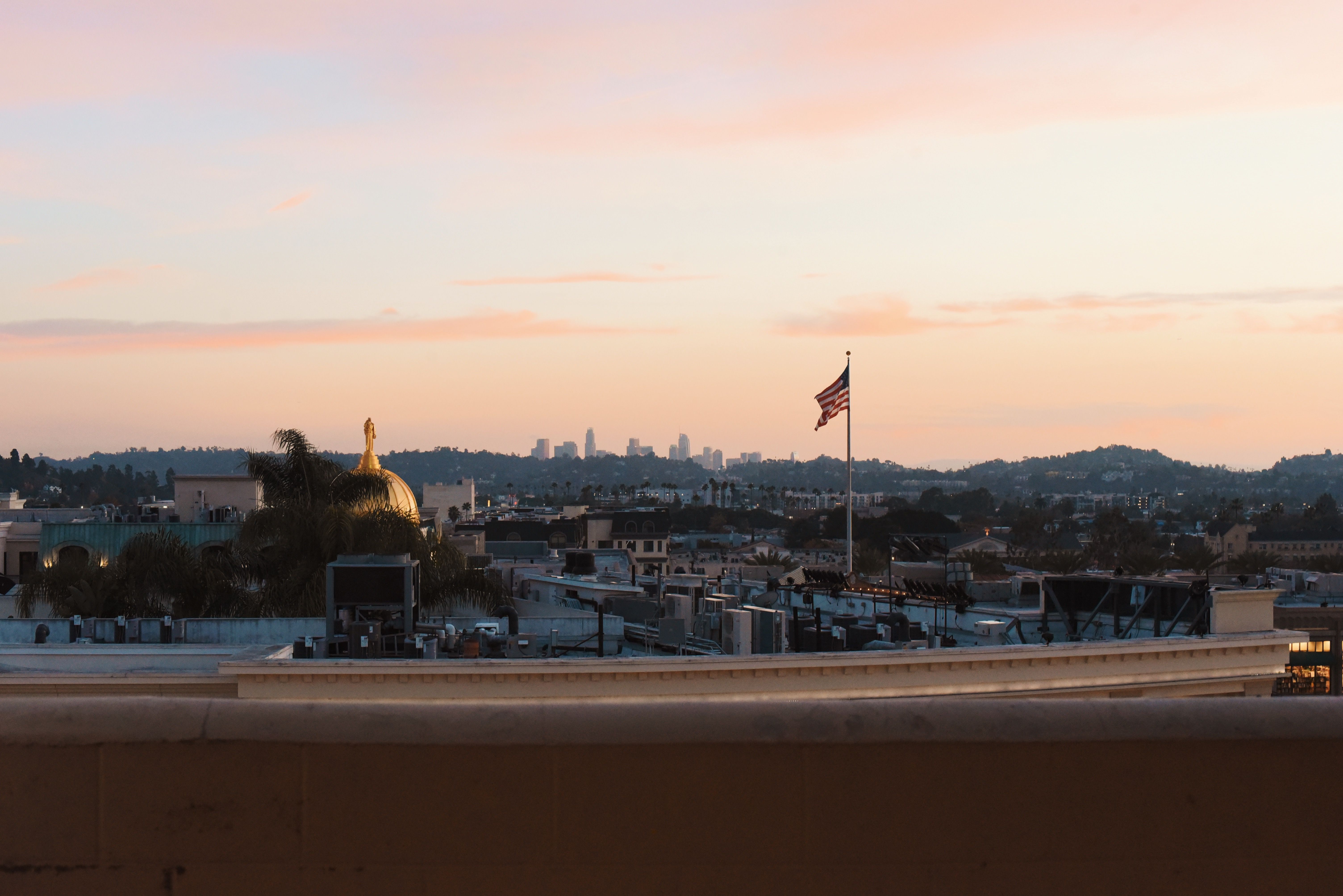 Beautiful Los Angeles skyline with an American flag during sunset, offering a warm and serene view.