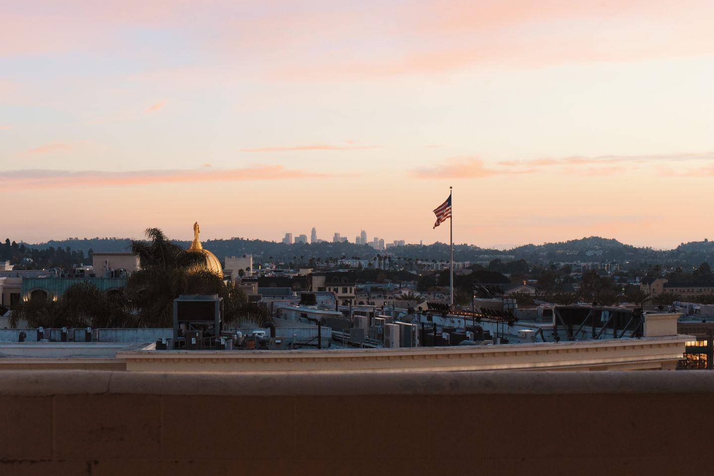 Los Angeles skyline at sunset from a rooftop with golden hour lighting