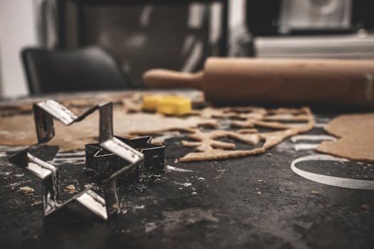 Close-up of star-shaped cookie cutters with rolling pin and dough, emphasizing the baking process.
