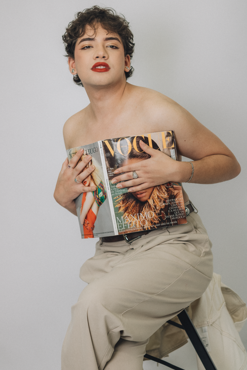 Free Person posing confidently with a fashion magazine in a minimalist studio. Stock Photo
