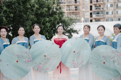 Free Group of women in traditional dress holding parasols, smiling outdoors. Stock Photo