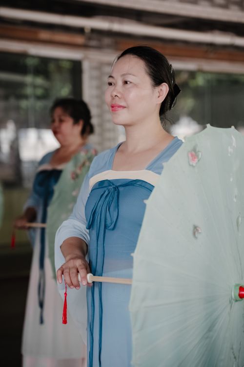 Free Women in traditional dress performing a cultural dance with parasols indoors. Stock Photo