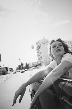 Woman enjoying a street drive in Los Angeles, capturing summer freedom in black and white.