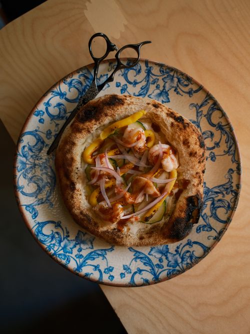 Free Gourmet flatbread pizza topped with shrimp and onions on a classic floral plate. Stock Photo