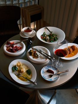 A collection of gourmet dishes and wine on a stylish round table.