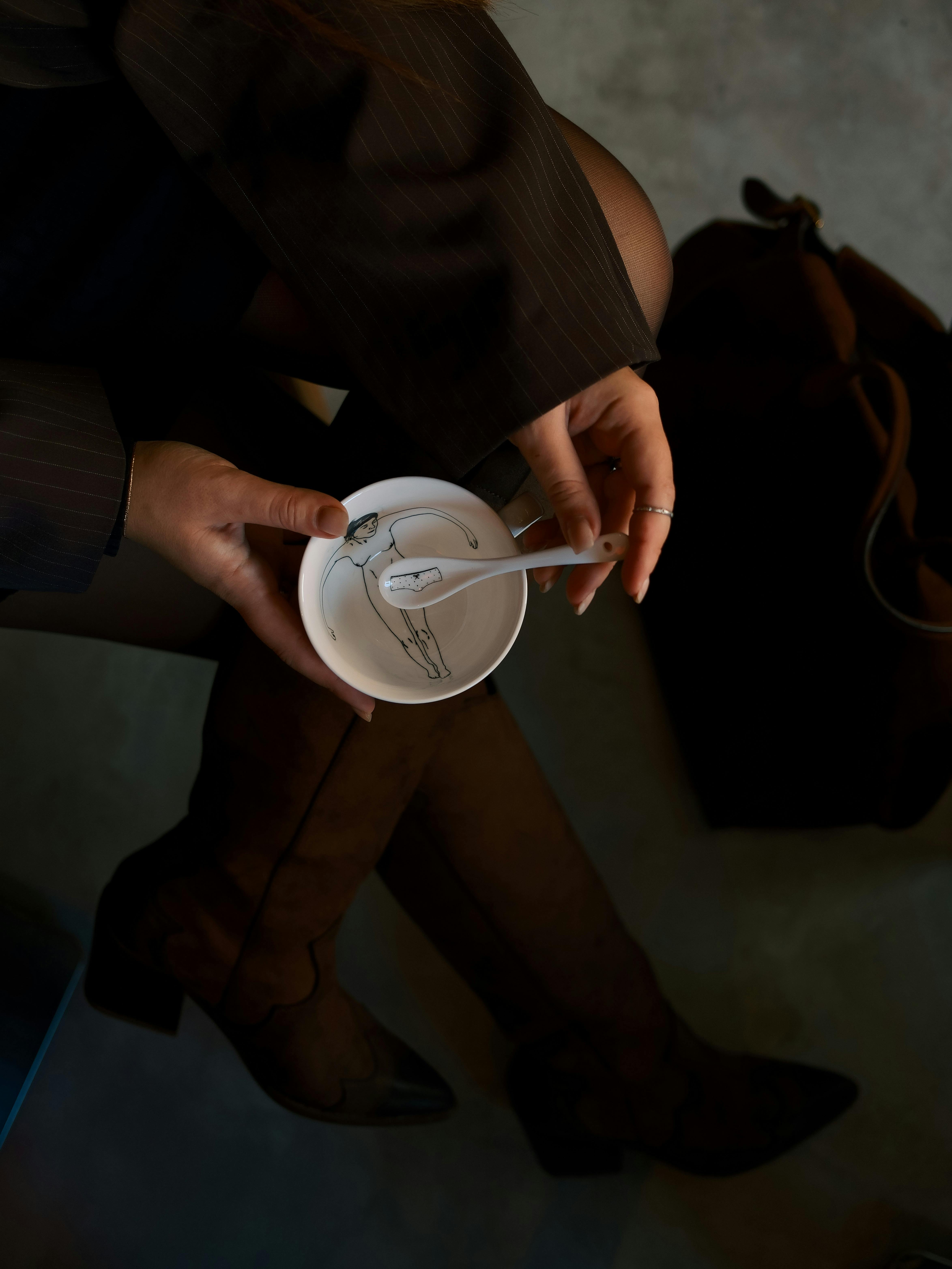 De franc Dona elegant sostenint una tassa de cafè, amb botes marrons, vista des de dalt. Foto d'estoc