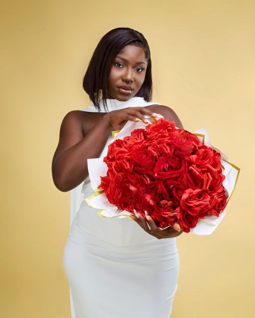 Free Stylish portrait of an elegant woman holding a vibrant red roses bouquet against a soft background. Stock Photo