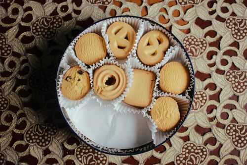 Free Top view of assorted butter cookies in a round tin on a decorative tablecloth. Stock Photo