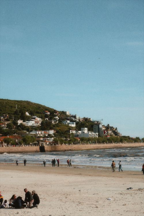 Free Scenic beachside with people, coastal homes, and serene ocean view. Stock Photo