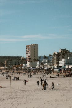 Lively scene at Venice Beach with people enjoying a sunny day, palm trees, and beachfront buildings.