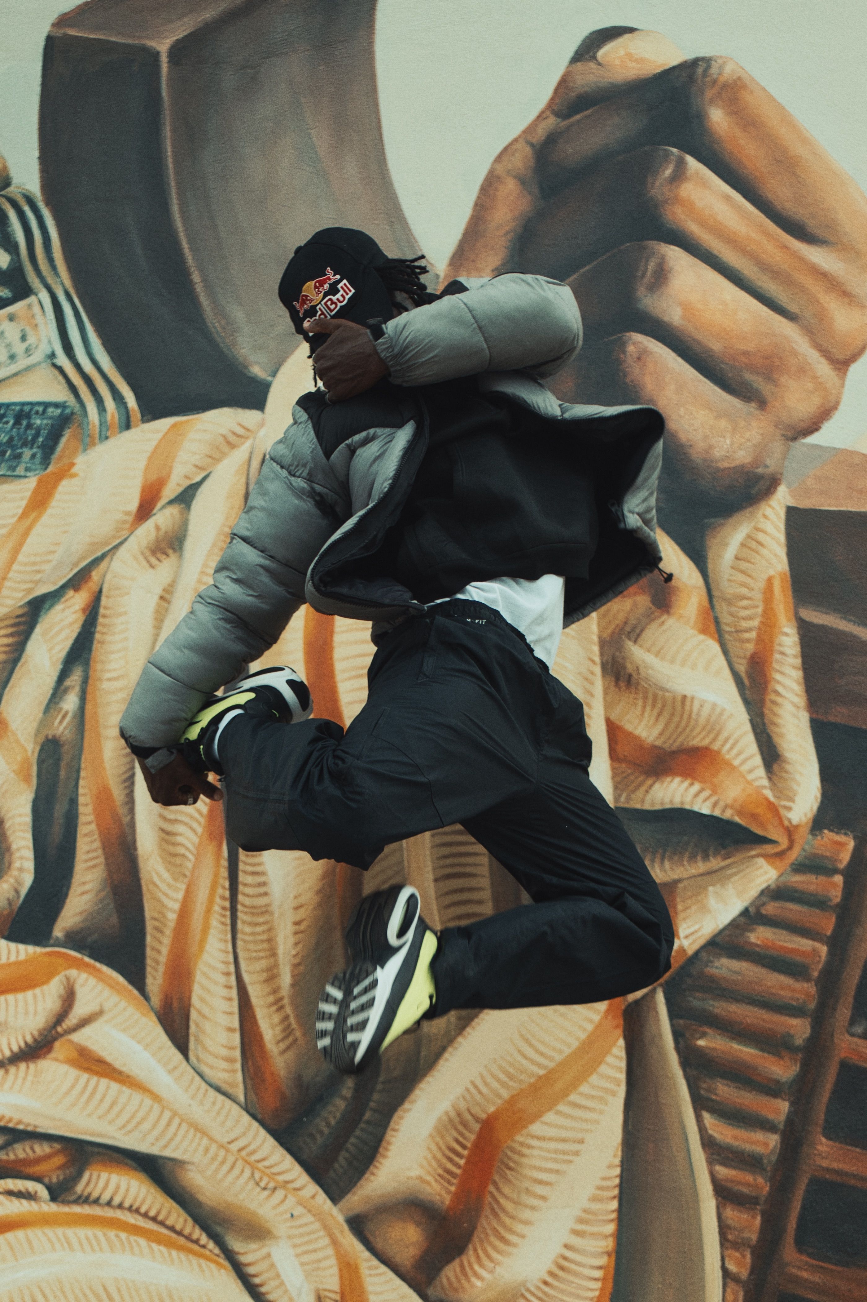 A dancer mid-jump in front of a colorful urban mural, exuding energy and style.