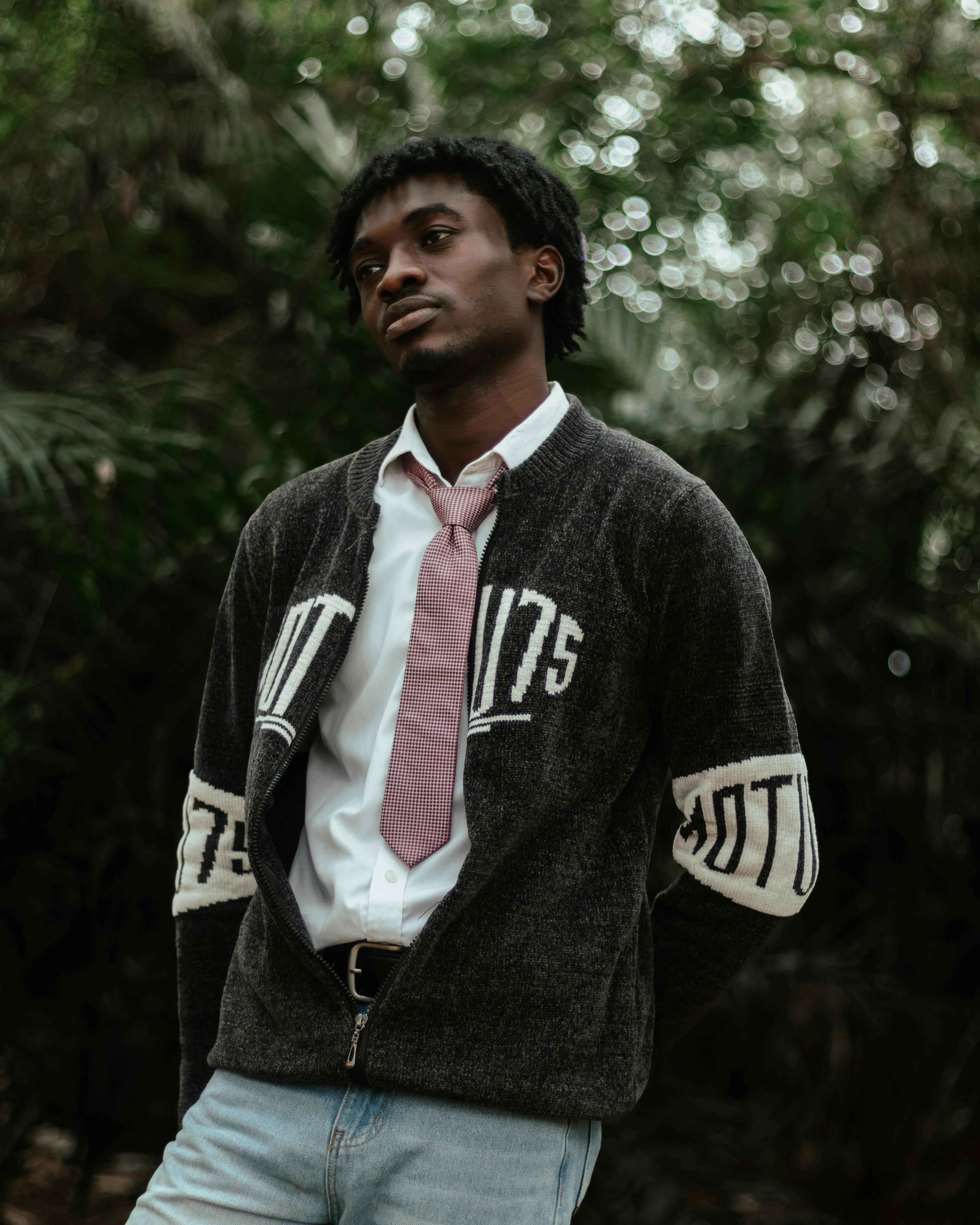 Fashionable young man in casual wear posing confidently in an outdoor, serene setting.