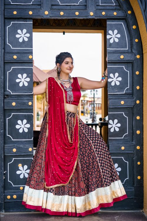 Free Elegant Indian woman in vibrant traditional attire posing outdoors in a historic setting. Stock Photo
