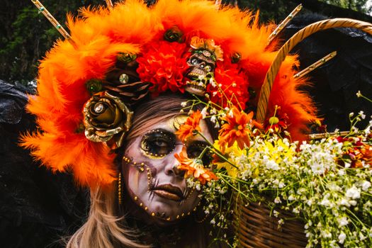 A striking Day of the Dead costume with vivid orange feathers and floral elements.
