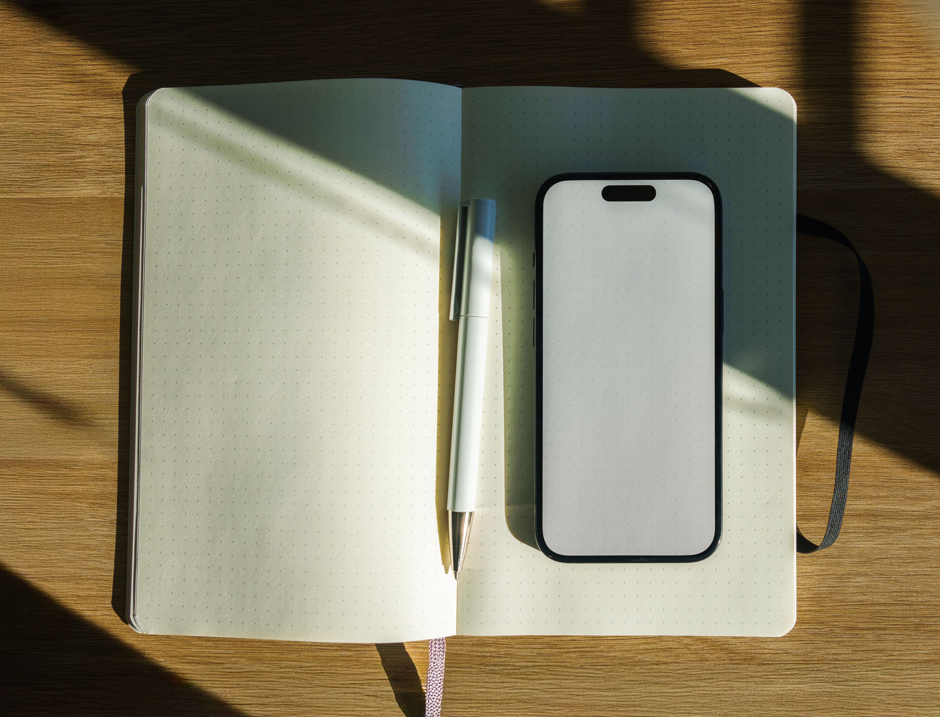 Sunlit Workspace with Notebook and Smartphone · Free Stock Photo