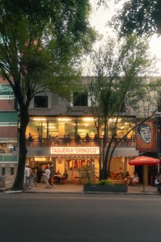 Street view of Taqueria Orinoco in vibrant Mexico City, showcasing its bustling atmosphere at dusk.