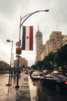 Street scene with Torre Latinoamericana and traffic in Mexico City, showcasing urban life.