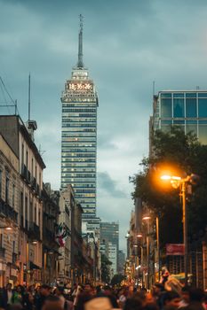 Crowds fill the streets under the iconic Torre Latinoamericana as dusk settles over Mexico City.