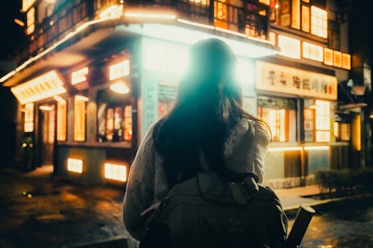 A person explores the vibrant street life near an illuminated building in Mexico City at night.