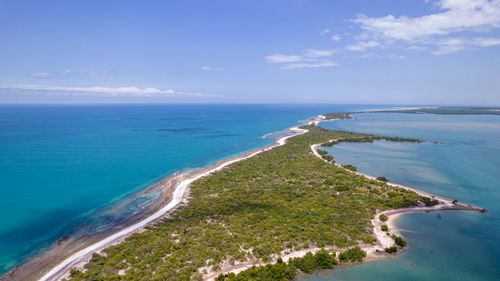 Free Scenic aerial view of a tropical island with lush greenery and turquoise ocean waters against a clear blue sky. Stock Photo