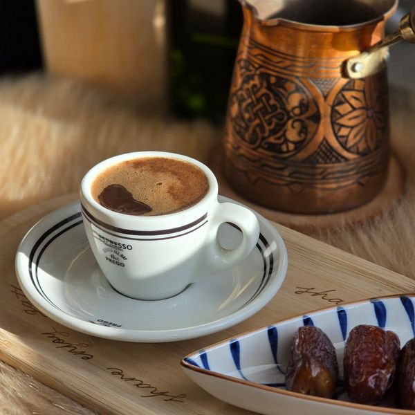 A cozy setting with Arabic coffee, dates, and traditional copper pot.