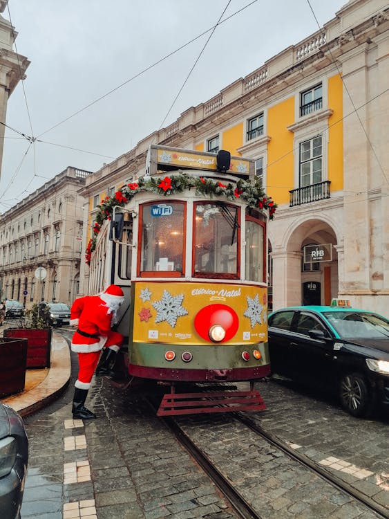 Santa Claus About to Enter Yellow Tram Beside Buildings