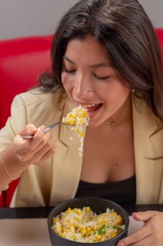 Woman savoring a bowl of rice with vegetables, enjoying her meal.
