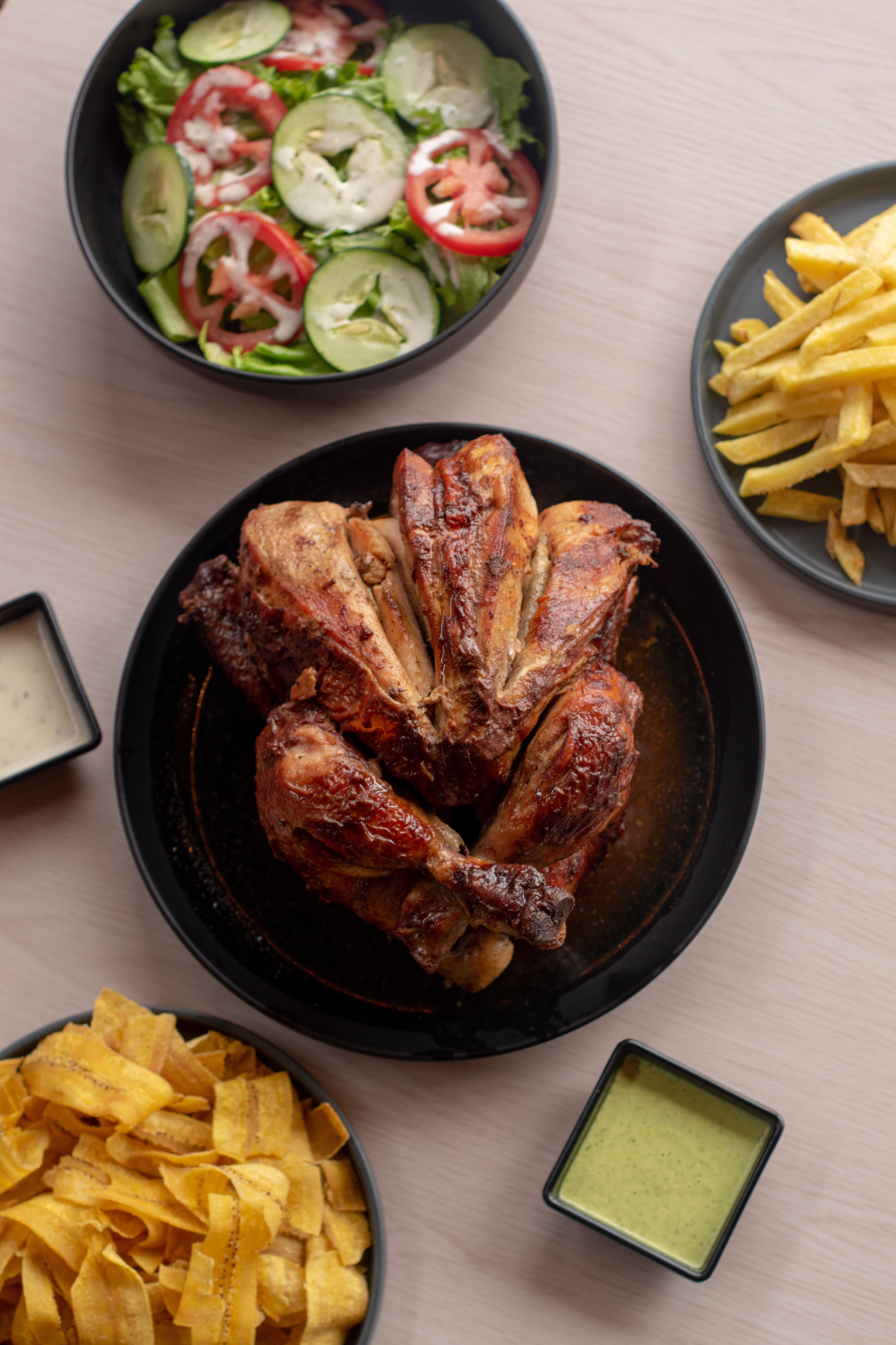 Savory roasted chicken served with fresh salad, fries, and sauces.