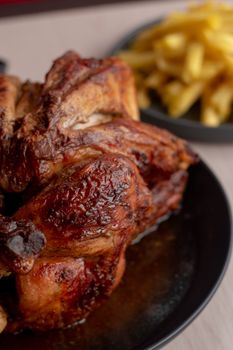 Delicious roasted chicken served with crispy golden fries on a dark plate.