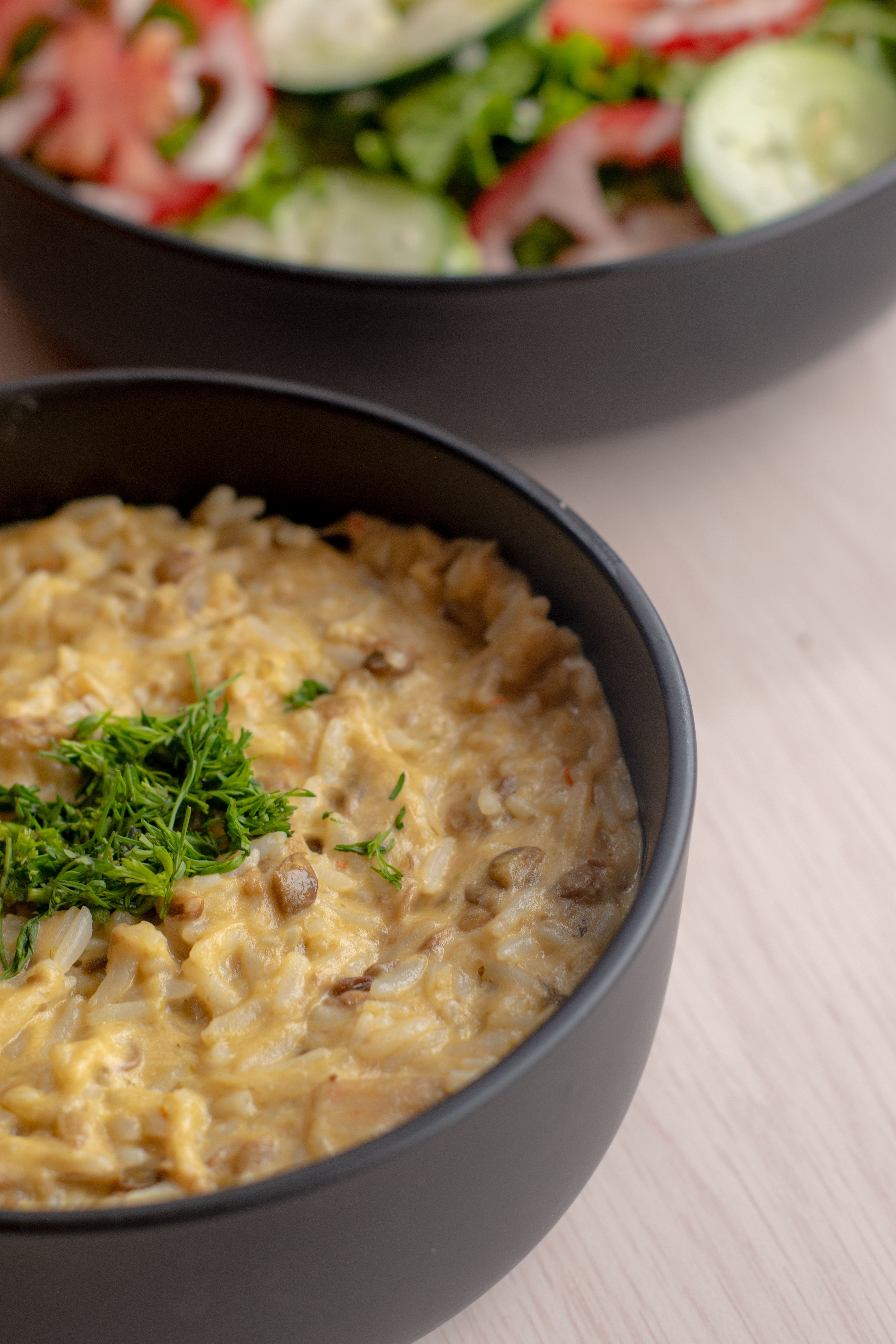 Delicious creamy risotto in a black bowl garnished with fresh herbs. Perfect gourmet meal.