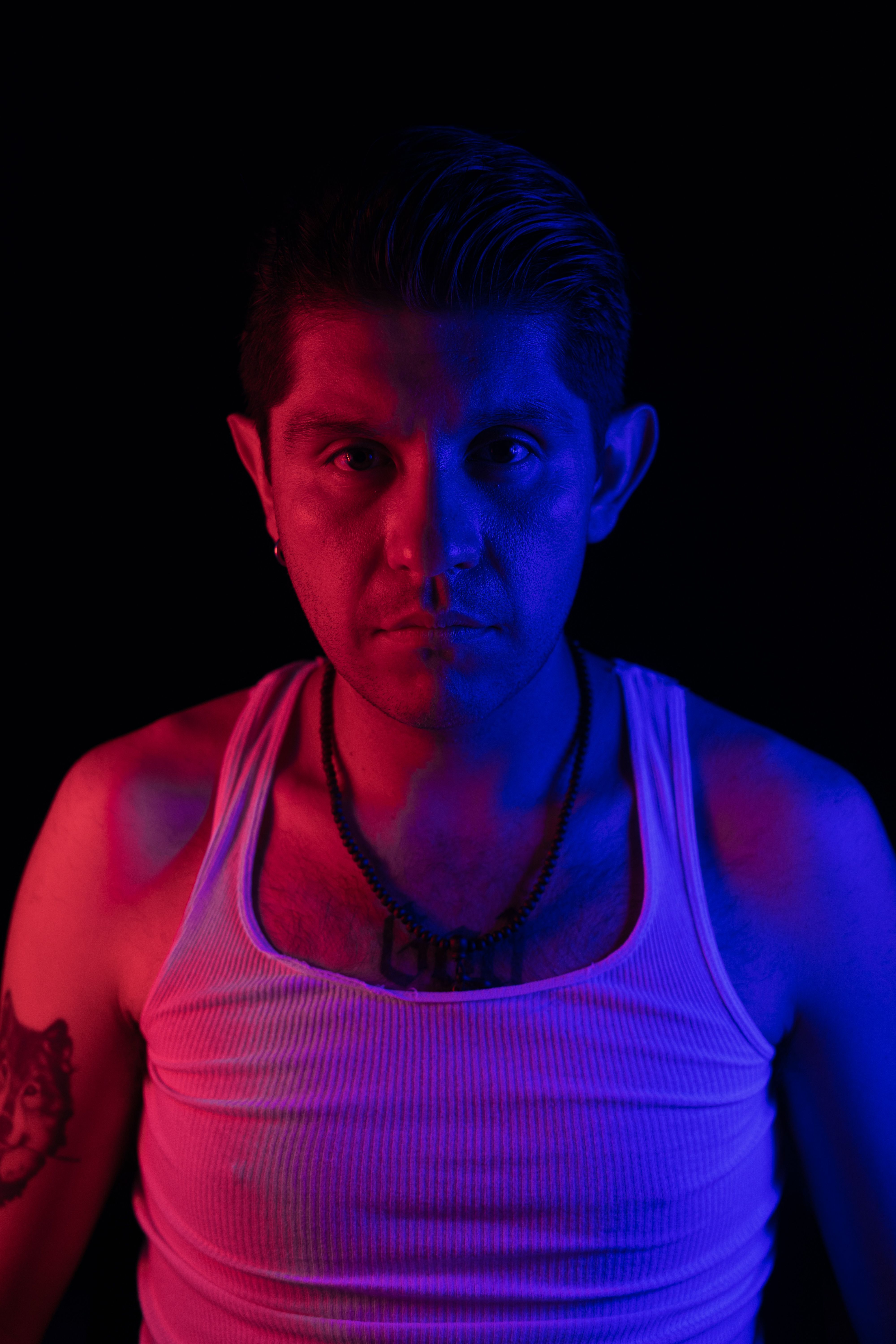 Striking portrait with intense red and blue lighting contrasts for a dramatic effect.