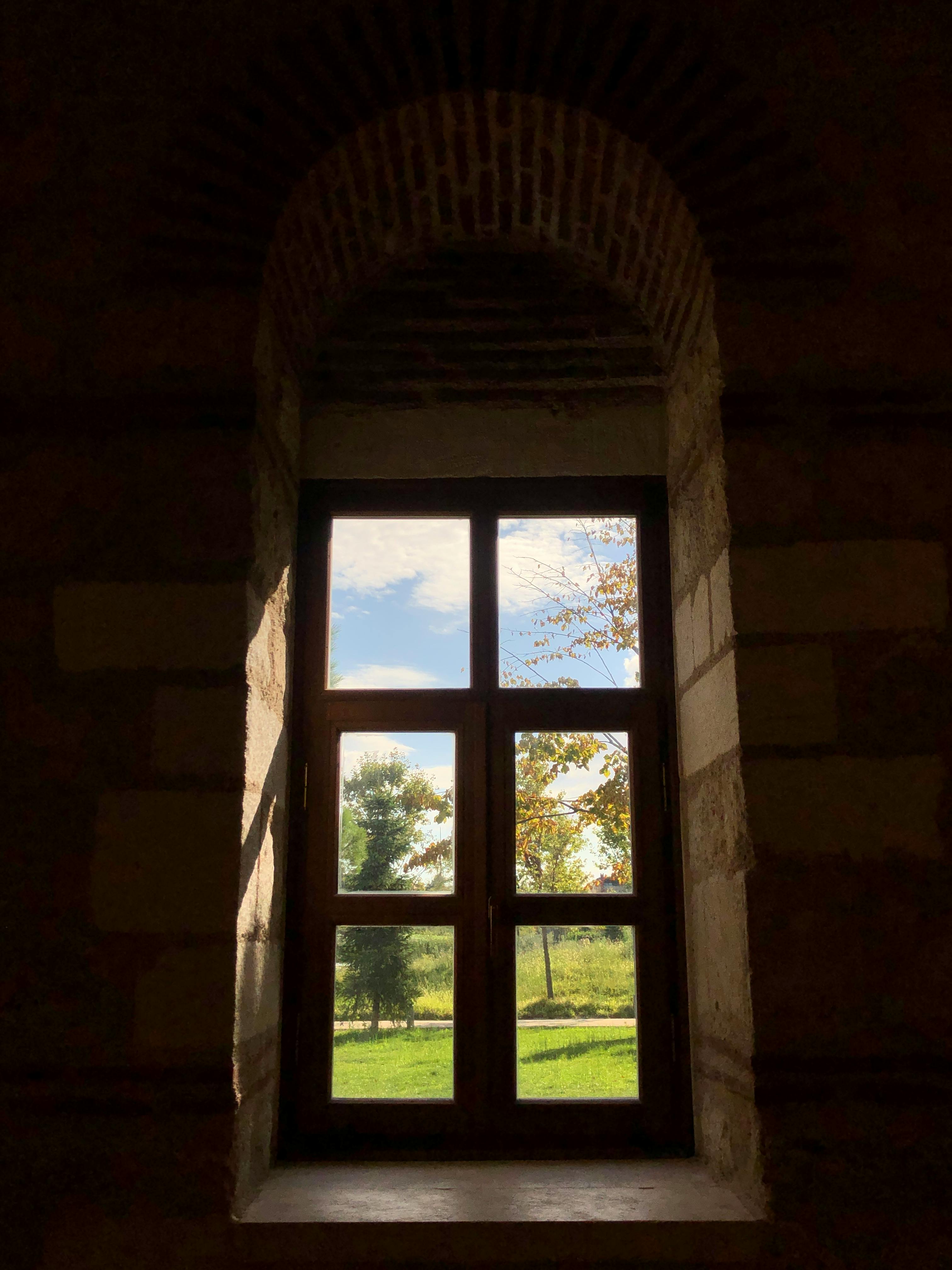 透过历史悠久的拱形窗户，阳光投射出阴影，欣赏自然景观