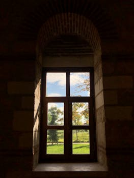 透过历史悠久的拱形窗户，阳光投射出阴影，欣赏自然景观