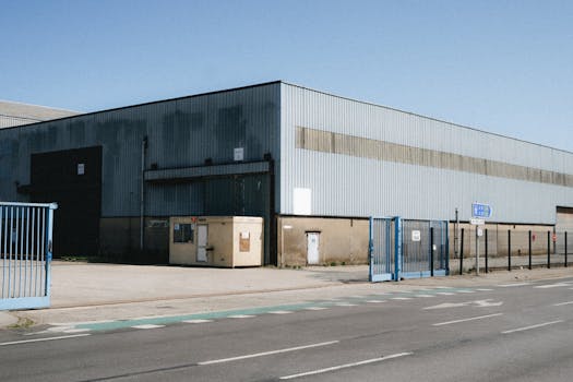 View of a large industrial warehouse in Dunkerque, showcasing its metal structure and broad entrance. Clear sky day.