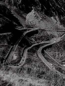 Black and white aerial shot of the winding Transfagarasan Highway in the Carpathian Mountains.
