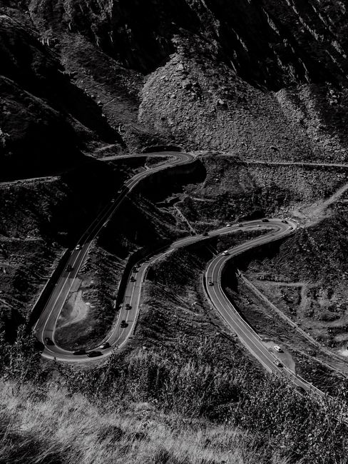 Black and white aerial shot of the winding Transfagarasan Highway in the Carpathian Mountains.