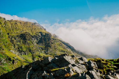 Free Breathtaking view of a lush, green mountain against a bright blue sky and clouds. Stock Photo