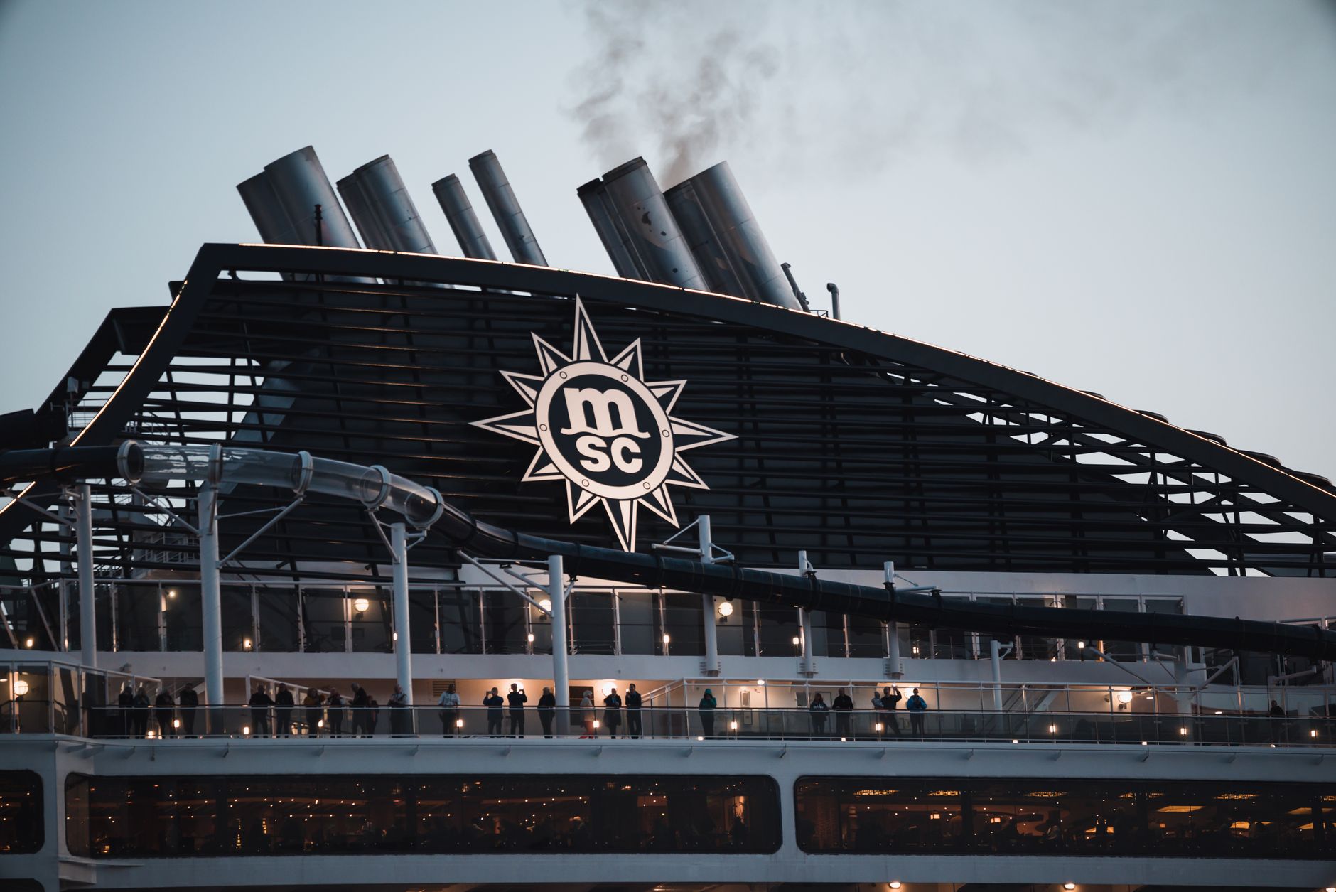 Passagiere genießen die Abendansicht auf dem Deck des MSC Kreuzfahrtschiffes mit Schornsteinen.