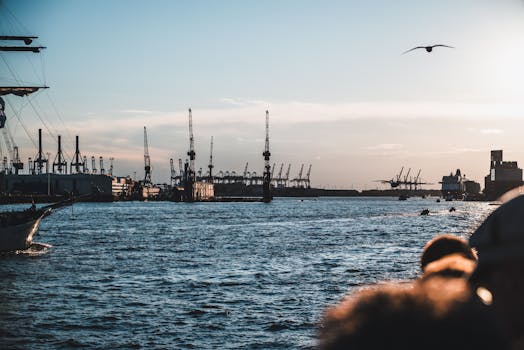Industrial harbor scene with cranes at sunset, showcasing a vibrant waterfront view.