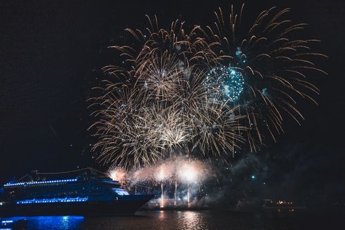 Free Vibrant fireworks light up the night sky above a majestic cruise ship on open water. Stock Photo