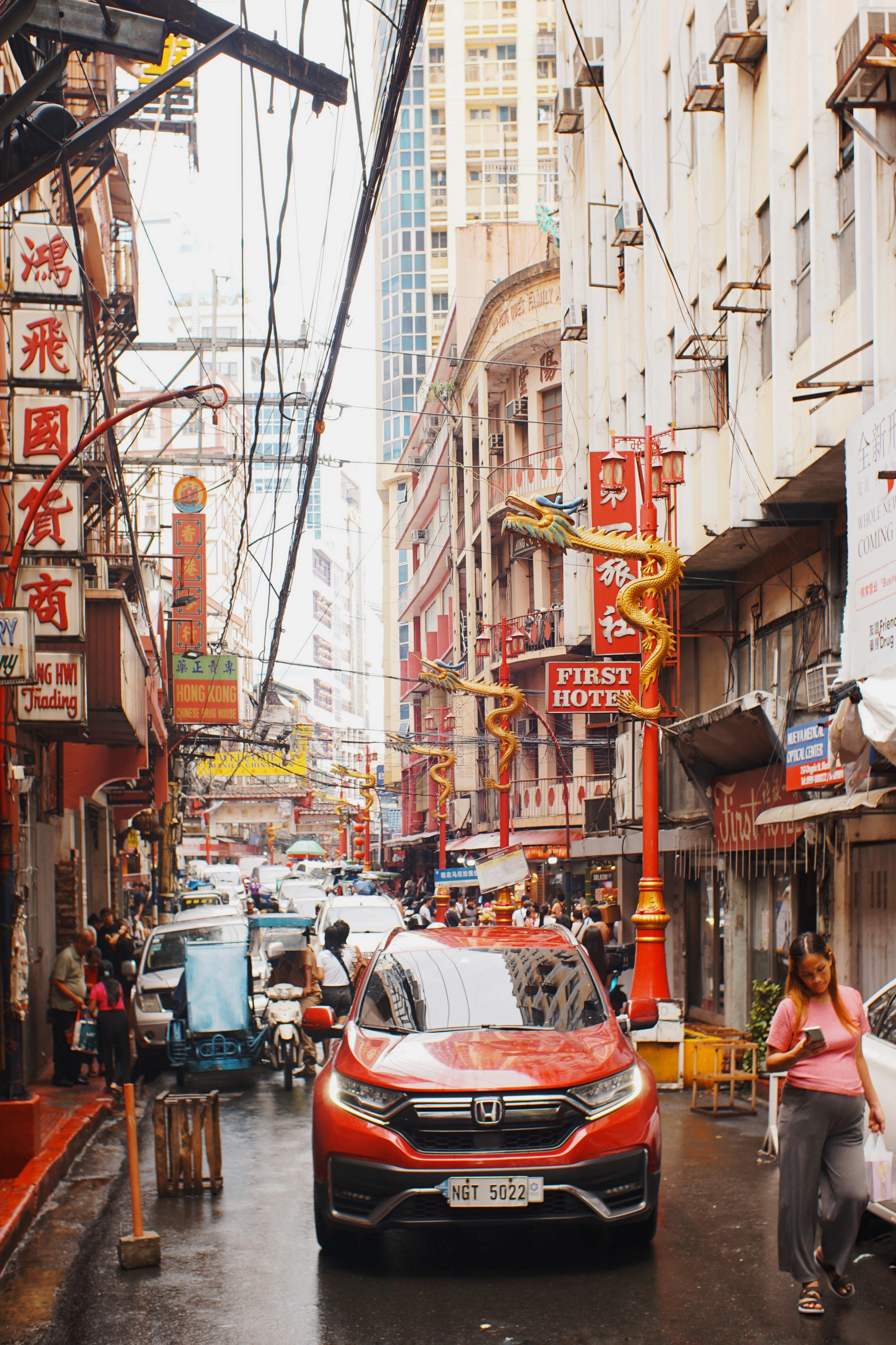 Busy street in Chinatown featuring vibrant signs and multiple vehicles.