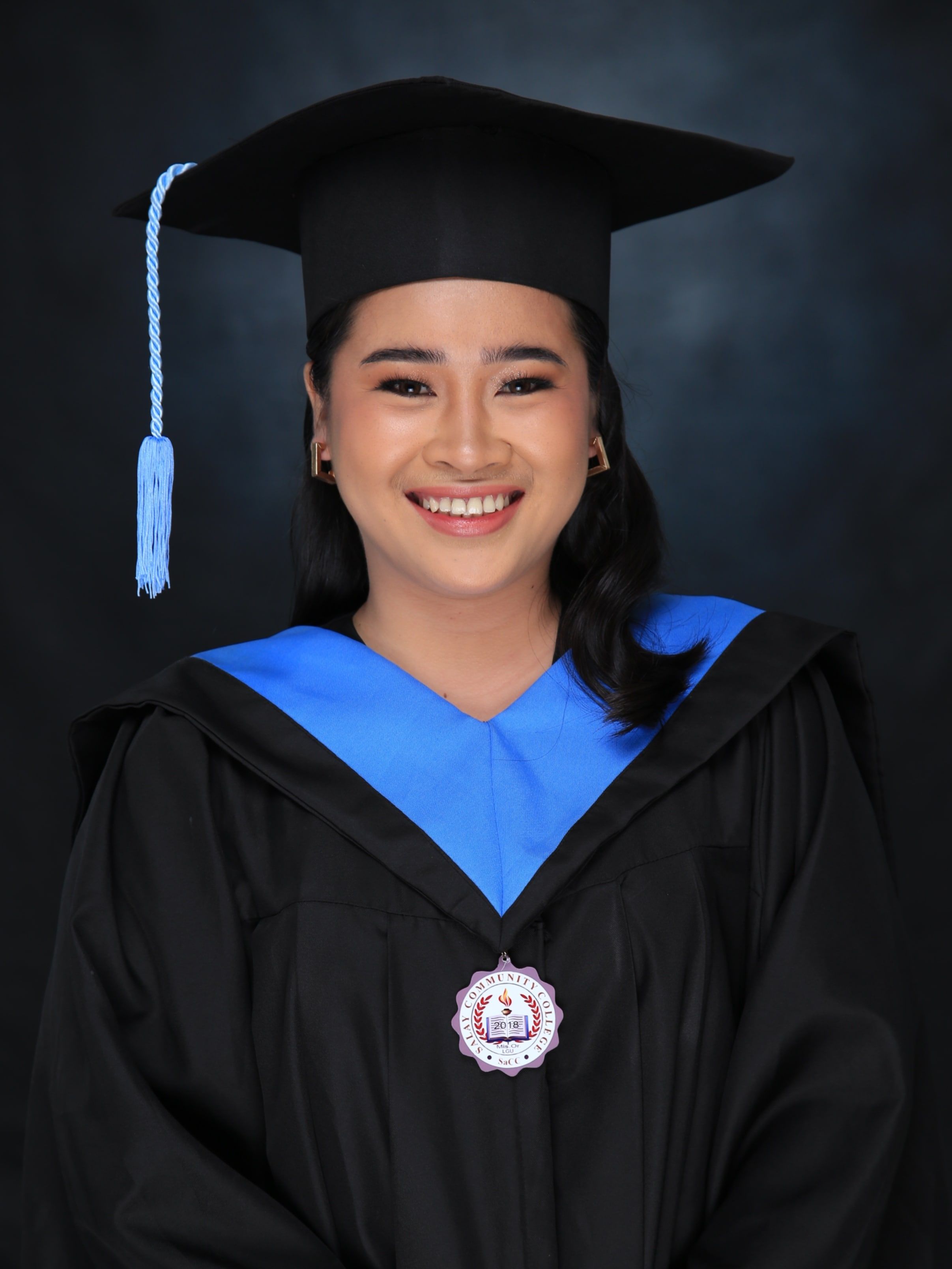 Smiling graduate in black and blue academic regalia, symbolizing success.