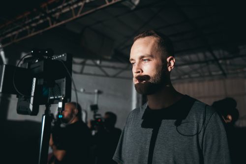 Free Man in shadows thoughtfully gazing while working in a dimly lit industrial space. Stock Photo