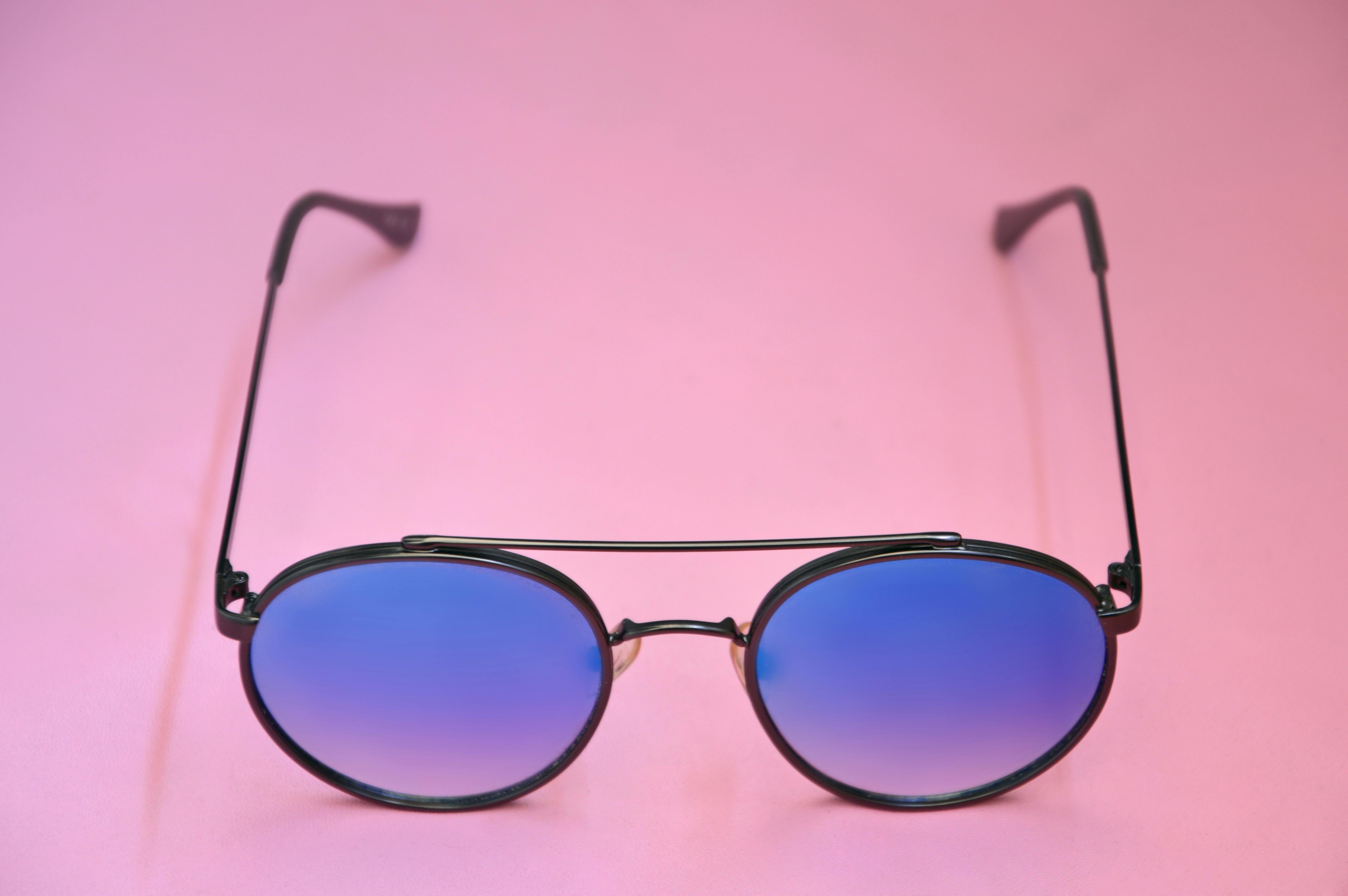 Gratis Elegantes gafas de sol redondas con lentes azules sobre un fondo rosa suave, perfectas para temas de moda. Foto de stock