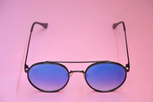 Free Stylish round sunglasses with blue lenses on a soft pink backdrop, perfect for fashion themes. Stock Photo
