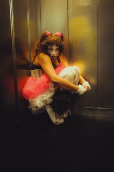 A spooky clown in Halloween cosplay crouches in an elevator, creating a chilling atmosphere.