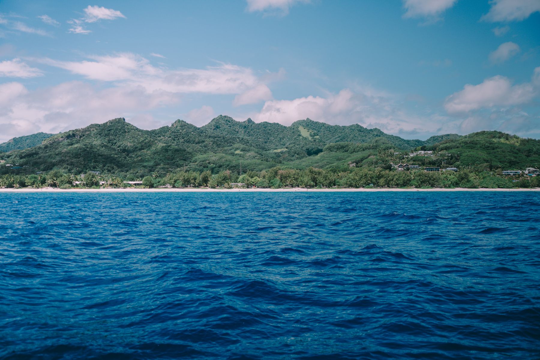 Green Cook Islands coastline beneath a bright sky