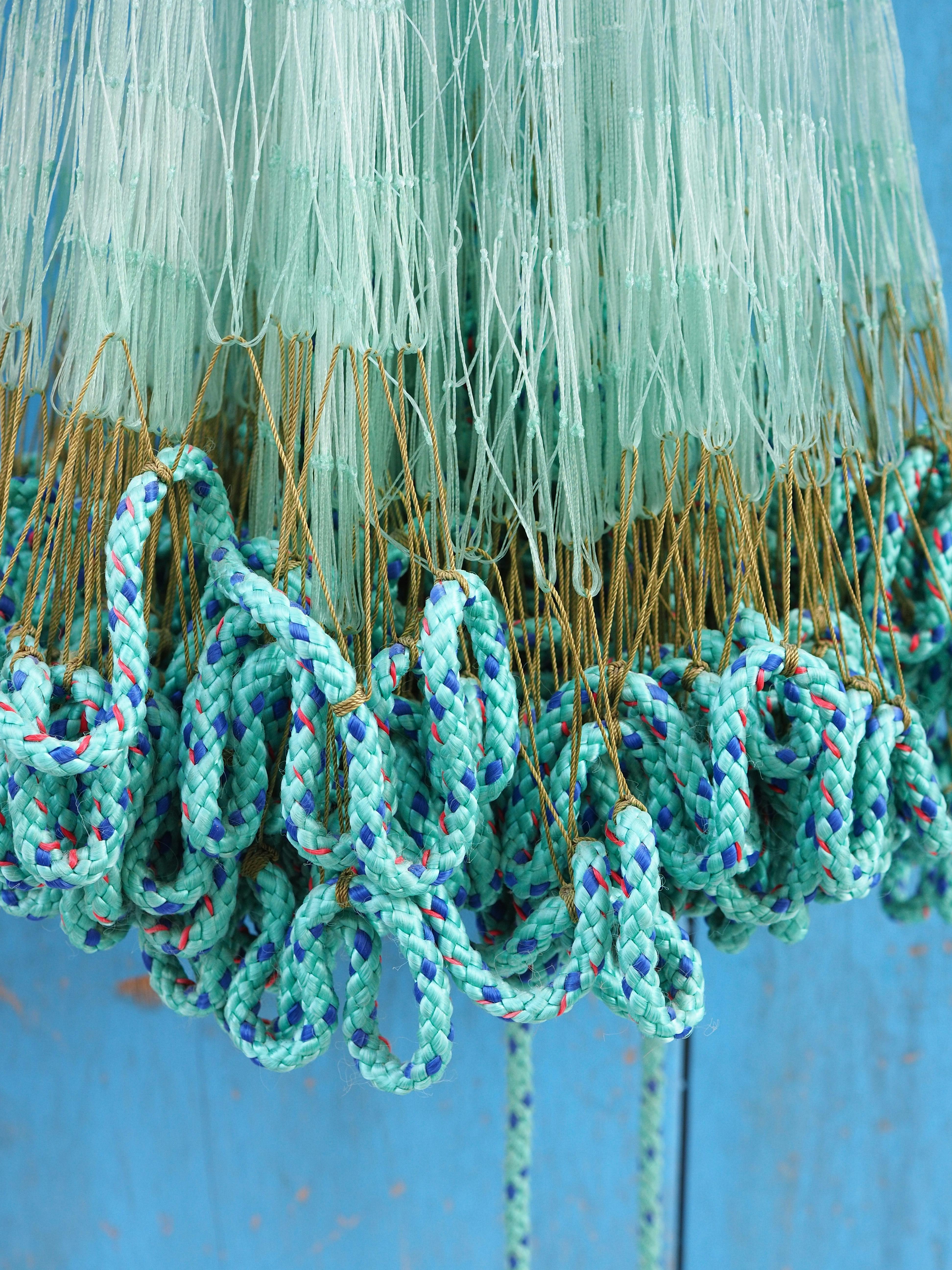Close-up of vibrant aqua blue fishing nets and ropes hanging in Doha, Qatar.