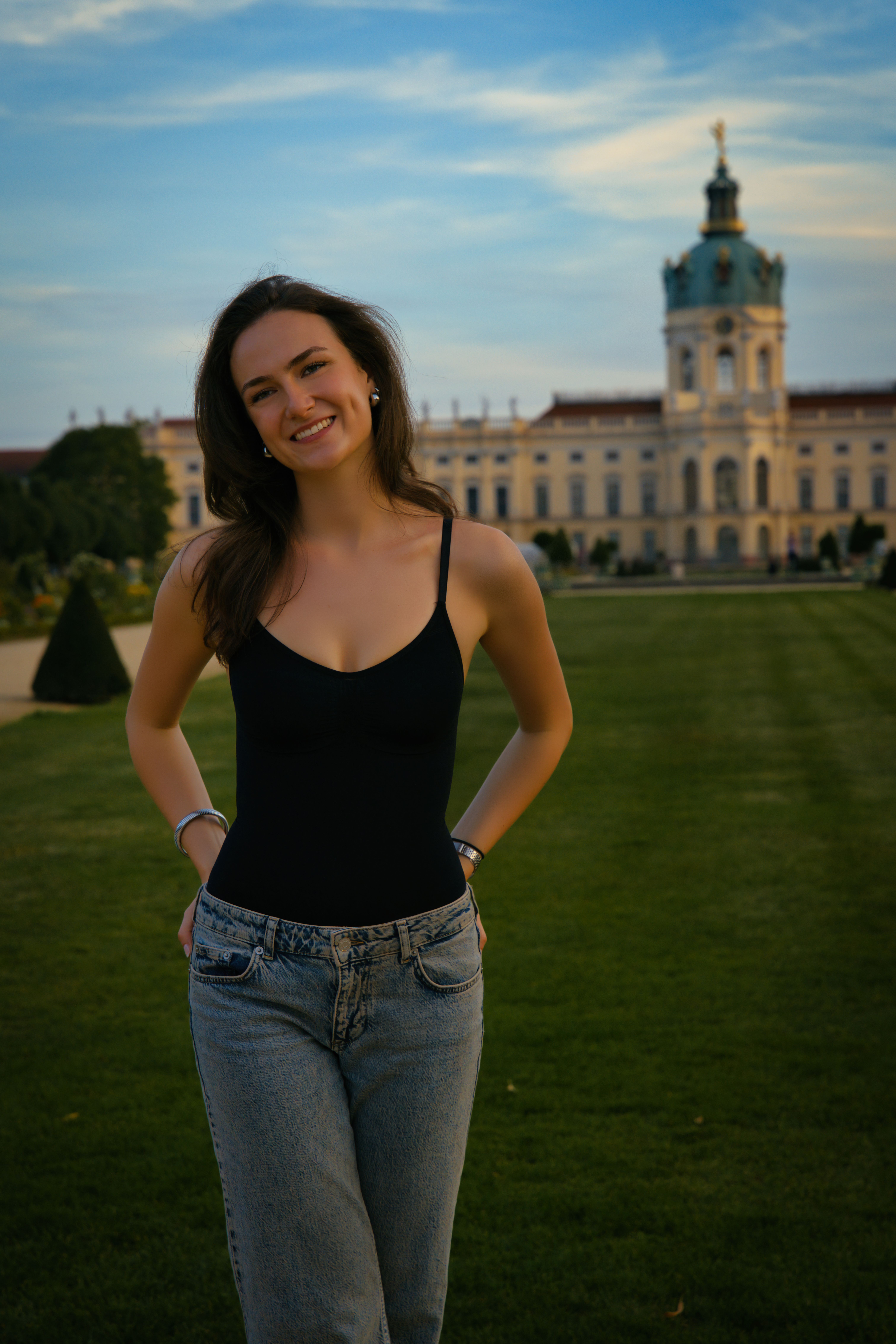 Cheerful woman posing at Charlottenburg Palace in Berlin, Germany, on a sunny day.