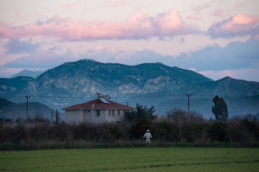 Scenic view of Dalyan at twilight with a house, mountains, and pink clouds.